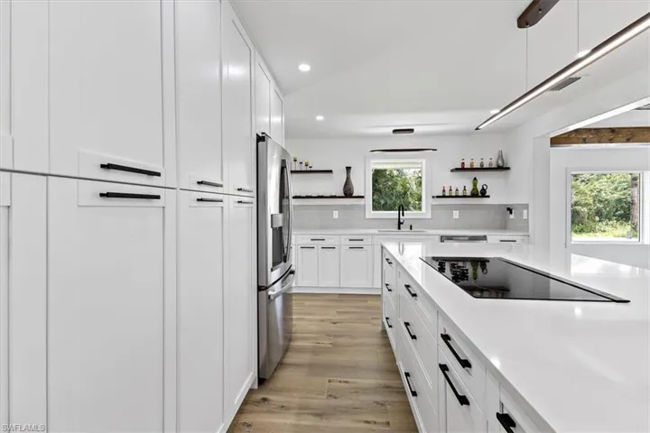 Kitchen featuring decorative backsplash, plenty of natural light, black electric cooktop, and light hardwood / wood-style flooring