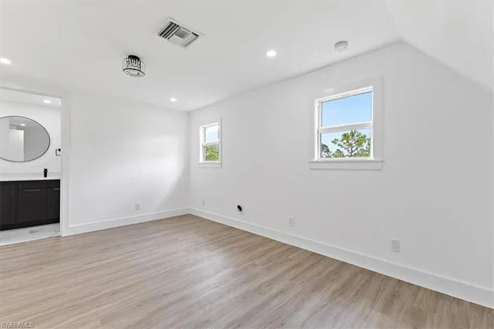 Unfurnished living room featuring lofted ceiling and light hardwood / wood-style floors