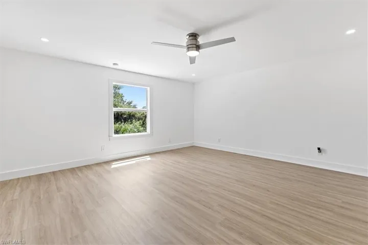 Empty room with ceiling fan and light hardwood / wood-style floors