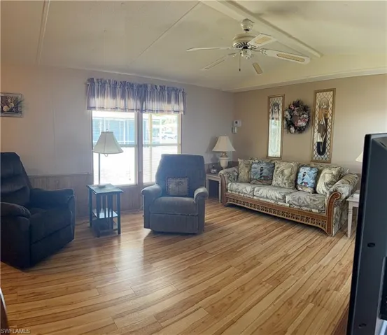 Living area is light filled with wood-look flooring, a ceiling fan