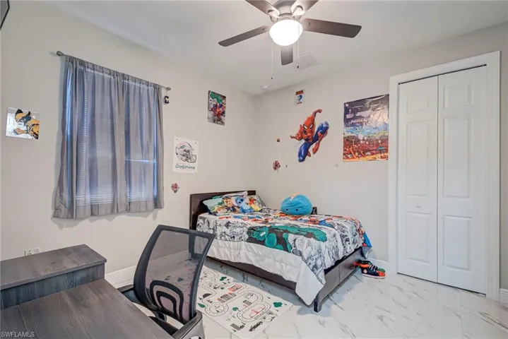 Bedroom with ceiling fan, a closet, and marble look tile flooring