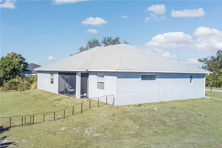 Rear view of house with stucco siding, roof with shingles, and a sunroom