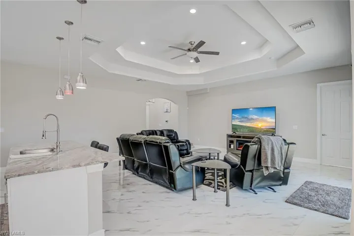 Home theater featuring arched walkways, light marble finish floors, recessed lighting, and ceiling fan