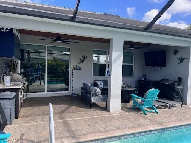 Rear view of property featuring a patio area, an outdoor pool, a ceiling fan, and stucco siding