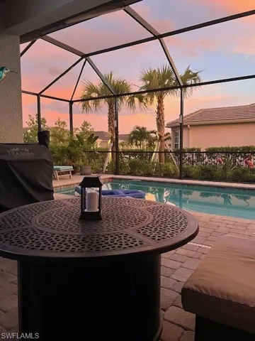Patio terrace at dusk with a sunroom, an outdoor pool, a lanai, and a patio area
