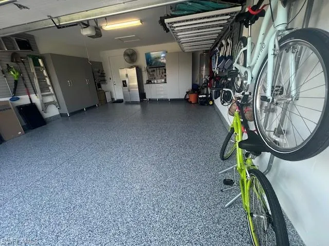 Garage with stainless steel refrigerator with ice dispenser and a garage door opener