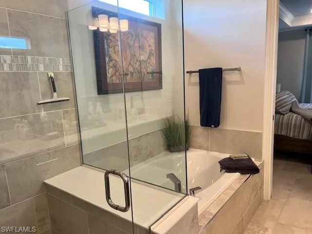 Ensuite bathroom featuring a garden tub, ornamental molding, and a stall shower