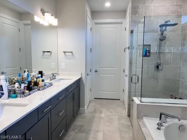 Bathroom featuring a stall shower, double vanity, and a bath