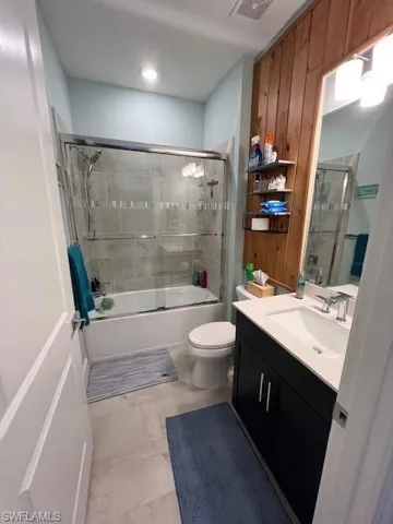 Bathroom with vanity and bath / shower combo with glass door