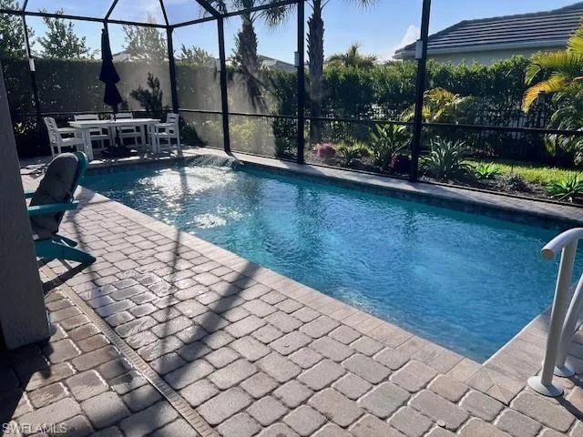 Outdoor pool featuring glass enclosure, a sunroom, outdoor dining space, and a patio area