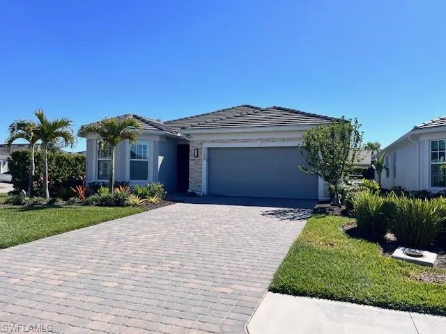 View of front of home with an attached garage, decorative driveway, stucco siding, a tiled roof, and stone siding