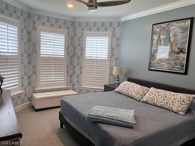 Carpeted bedroom featuring crown molding, a ceiling fan, and wallpapered walls
