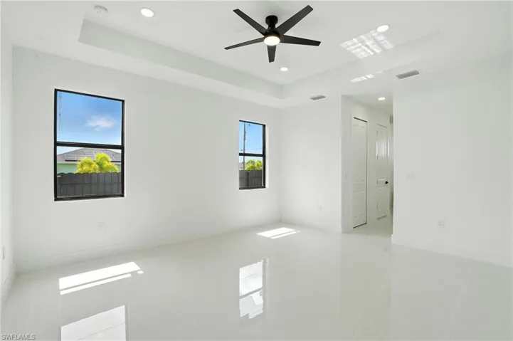 Empty room featuring a raised ceiling, recessed lighting, light tile patterned floors, a smoke detector, and ceiling fan