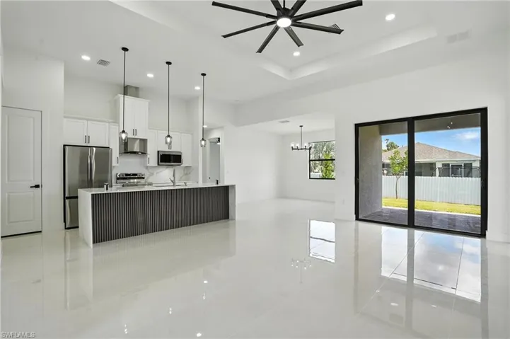 Kitchen with appliances with stainless steel finishes, light tile patterned floors, exhaust hood, open floor plan, and recessed lighting