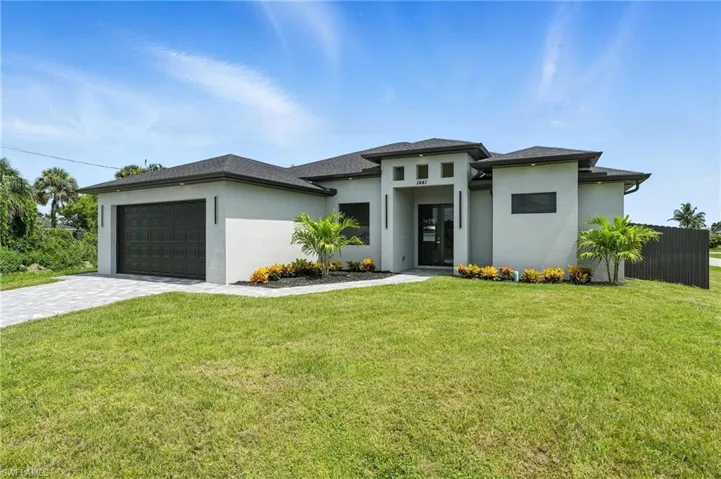 Prairie-style home with an attached garage, stucco siding, decorative driveway, and a front lawn