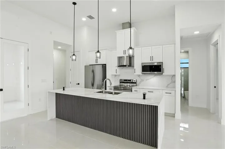 Kitchen with stainless steel appliances, white cabinets, wall chimney range hood, recessed lighting, and backsplash