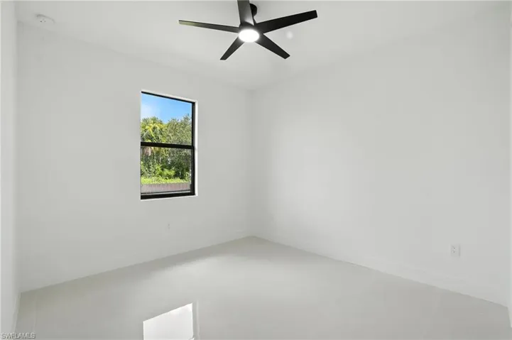 Empty room featuring a smoke detector, light tile patterned flooring, and a ceiling fan