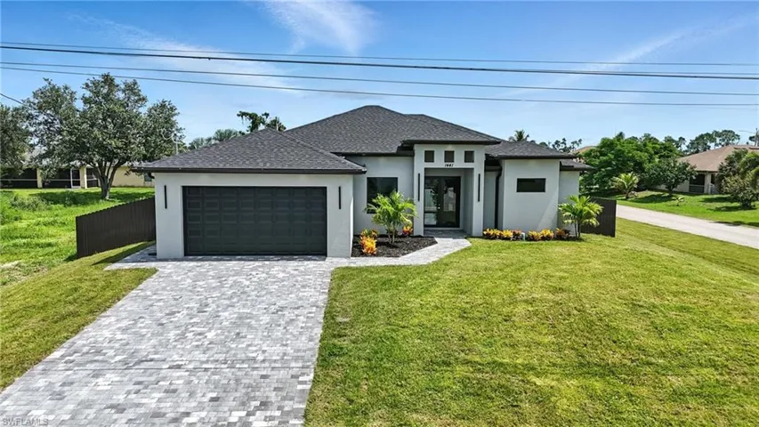 Prairie-style home featuring an attached garage, stucco siding, and decorative driveway