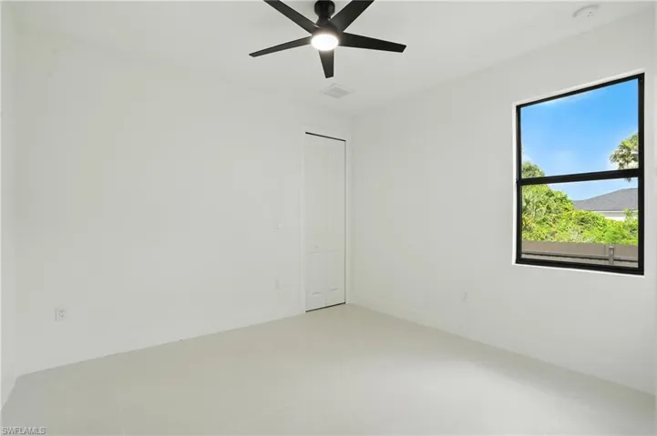 Empty room with a smoke detector, ceiling fan, and light tile patterned flooring