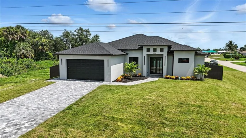 Prairie-style home featuring stucco siding, french doors, a garage, a front lawn, and decorative driveway