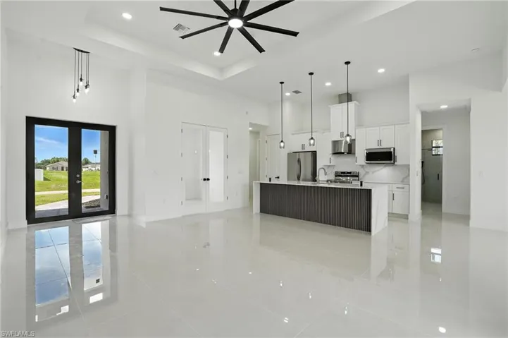 Kitchen featuring appliances with stainless steel finishes, a towering ceiling, extractor fan, light tile patterned floors, and open floor plan