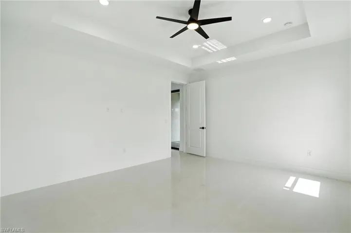 Unfurnished room featuring a raised ceiling, recessed lighting, light tile patterned floors, and ceiling fan