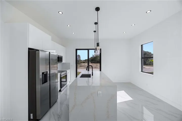 Kitchen featuring stainless steel appliances, white cabinets, light stone counters, modern cabinets, and light marble finish floors