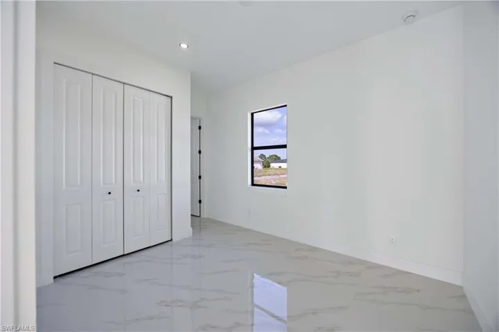 Unfurnished bedroom featuring a closet, light marble finish flooring, and recessed lighting