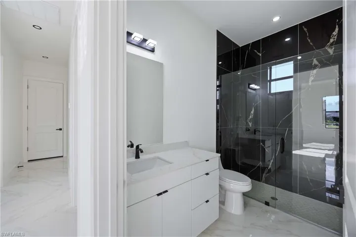 Full bath featuring a marble finish shower, vanity, recessed lighting, and light marble finish floors