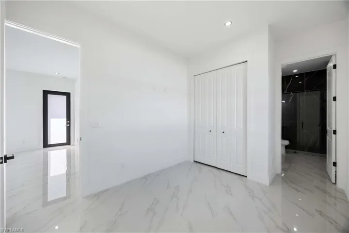 Unfurnished bedroom featuring recessed lighting, a closet, light marble finish floors, and connected bathroom