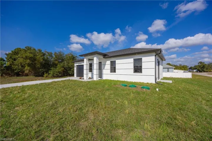 View of front of home with a garage, concrete driveway, and stucco siding