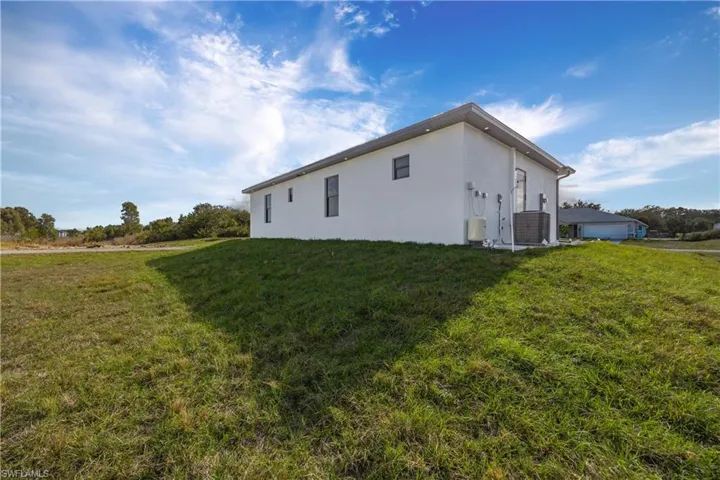 View of side of property featuring stucco siding and a lawn