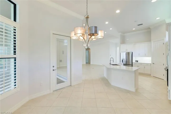 Kitchen with white cabinets, stainless steel fridge with ice dispenser, crown molding, a chandelier, and light tile patterned floors