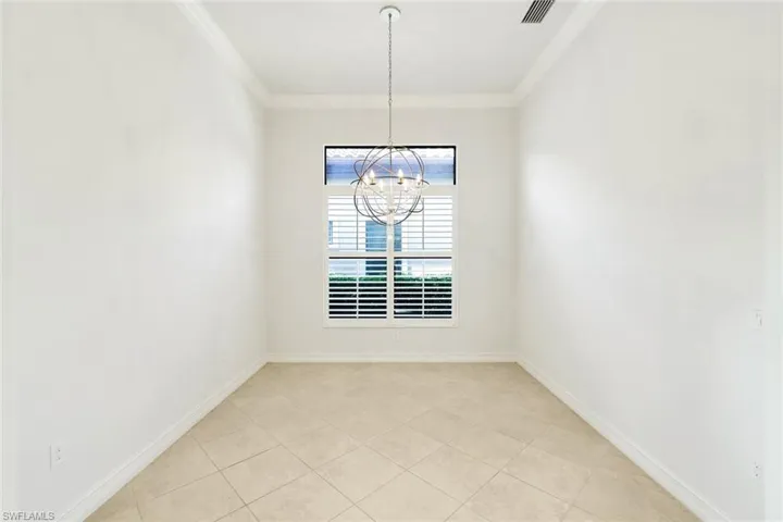 Unfurnished dining area featuring ornamental molding, light tile patterned floors, and suspended lighting
