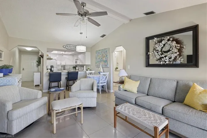 Tiled living room featuring arched walkways, ceiling fan, and a textured ceiling