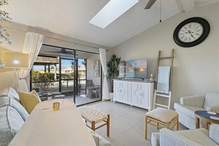 Living room featuring ceiling fan, a skylight, tile patterned flooring, and a textured ceiling