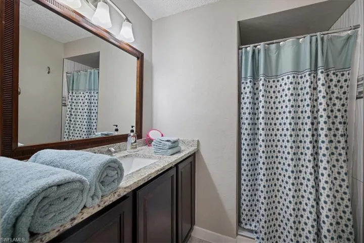 Bathroom featuring curtained shower, vanity, and a textured ceiling