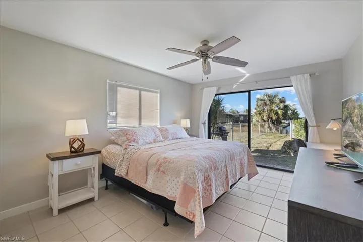 Bedroom with light tile patterned floors, a ceiling fan, and access to outside