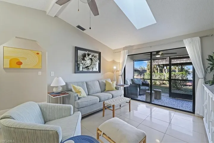 Living room featuring ceiling fan, a skylight, light tile patterned flooring, and a textured ceiling