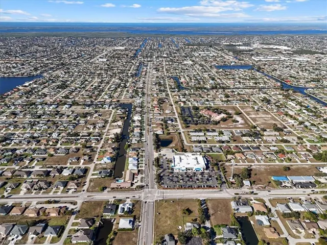 Aerial view of property and surrounding area featuring nearby suburban area and a nearby body of water