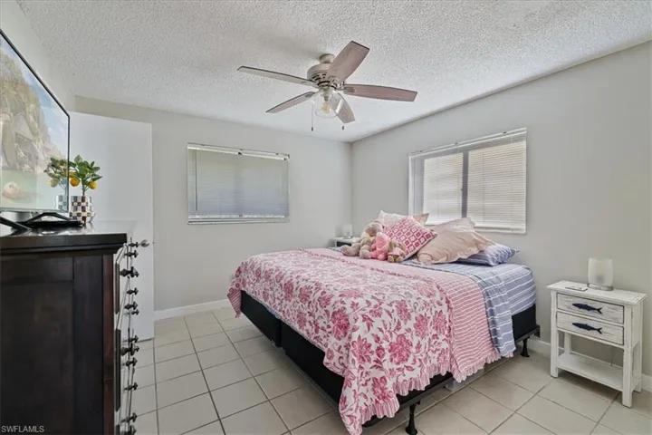 Bedroom featuring a textured ceiling, a ceiling fan, and light tile patterned floors