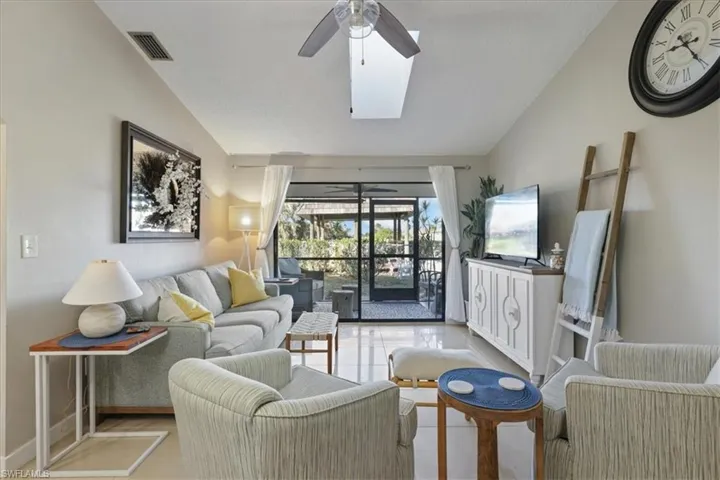 Living room featuring vaulted ceiling, a skylight, tile patterned floors, and ceiling fan