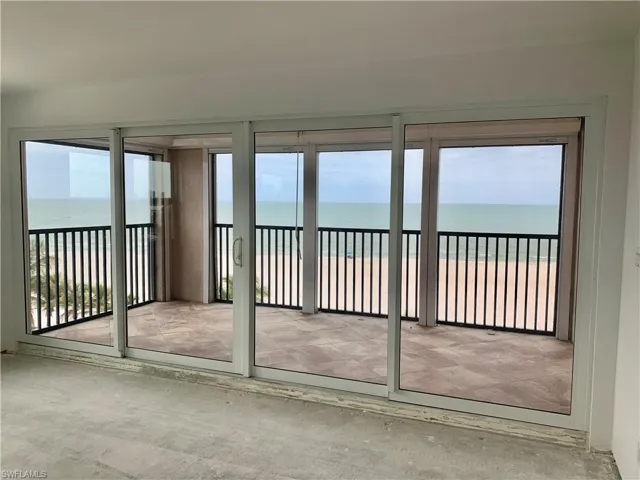 Unfurnished sunroom with view of water and beach and healthy amount of natural light