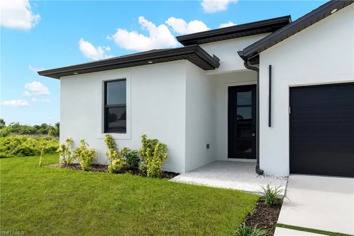 Contemporary exterior featuring white stucco, black trim, and a black front entry door with vertical window panels