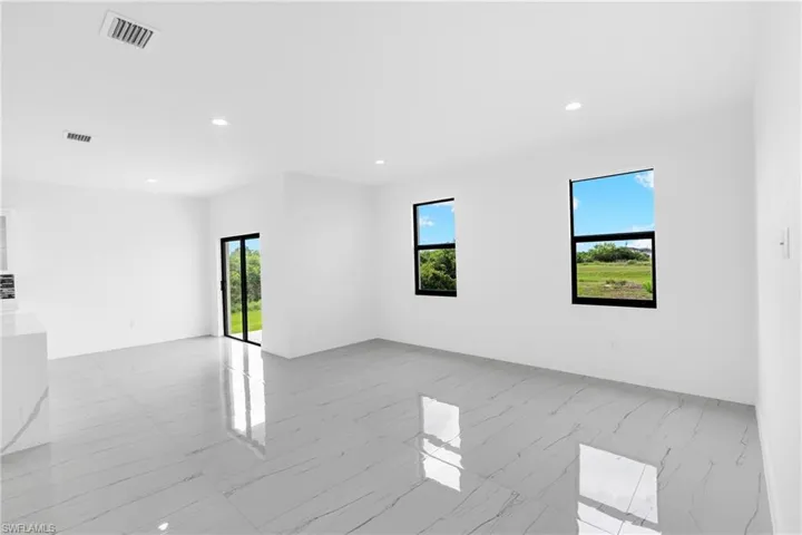 Open concept living space featuring large format grey and white veined tile flooring, recessed ceiling lighting, and crisp white walls