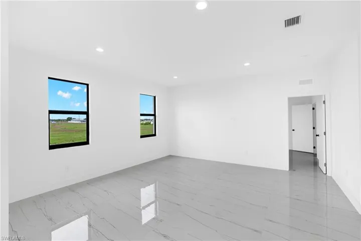 Spacious room featuring white walls, recessed ceiling lighting, and two windows with black frames