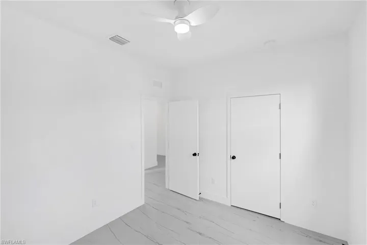 Room with light-toned walls, marblized tile flooring, and a ceiling fan