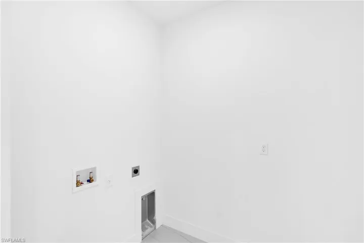 Dedicated utility space featuring washer and dryer hookups, electrical outlets, and white baseboards
