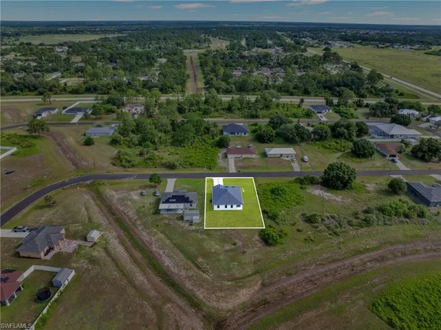 Aerial perspective showcasing a single-story residence with a dark shingle roof, white exterior siding, and an attached garage