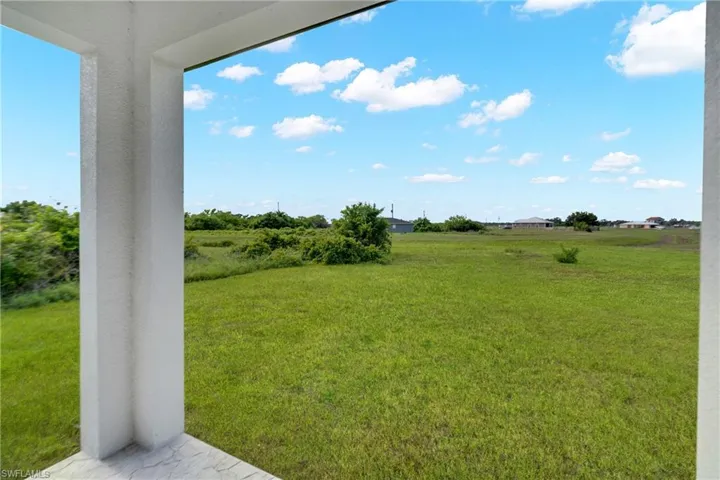 Spacious outdoor area featuring a wide expanse of green lawn and distant foliage